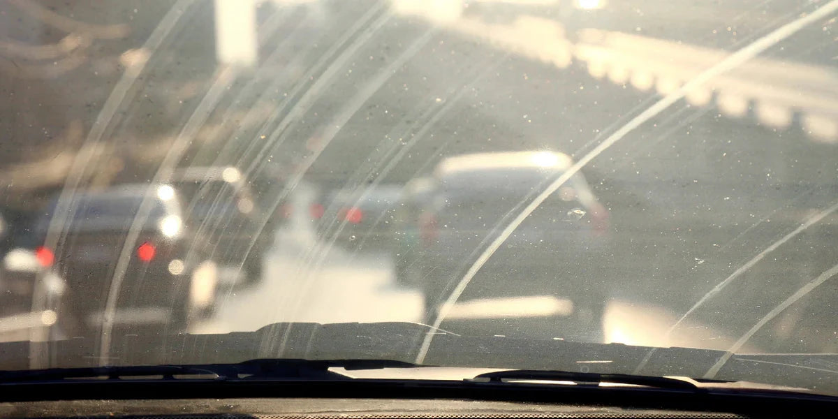 dirty windshield with greasy film visible under light, ammonia-free glass cleaner application on car windshield